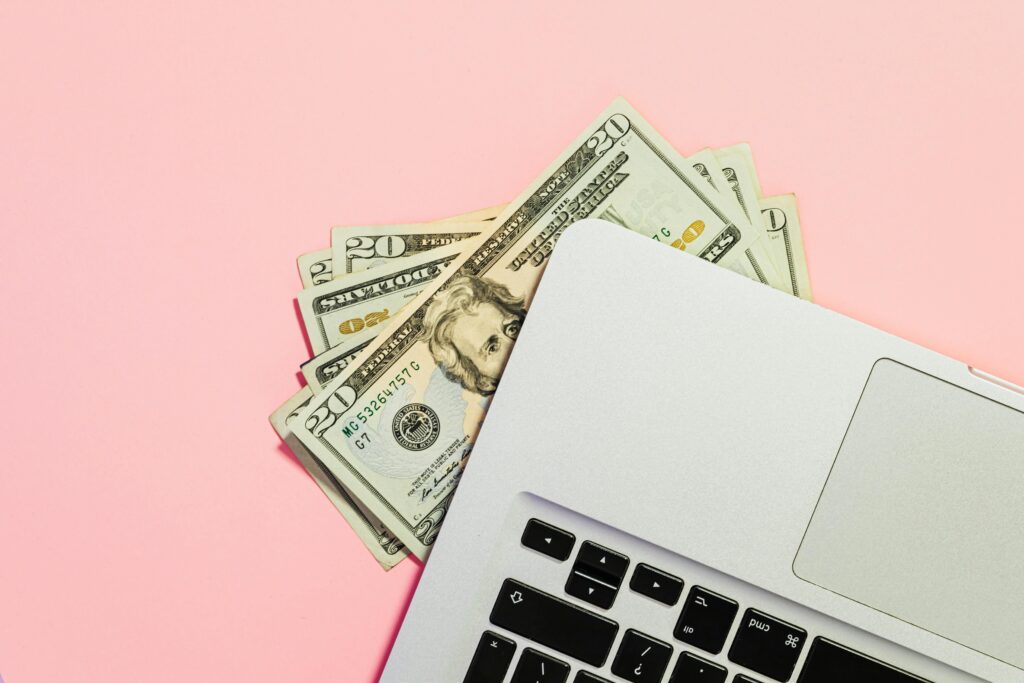 Money-under-laptop-pink-background